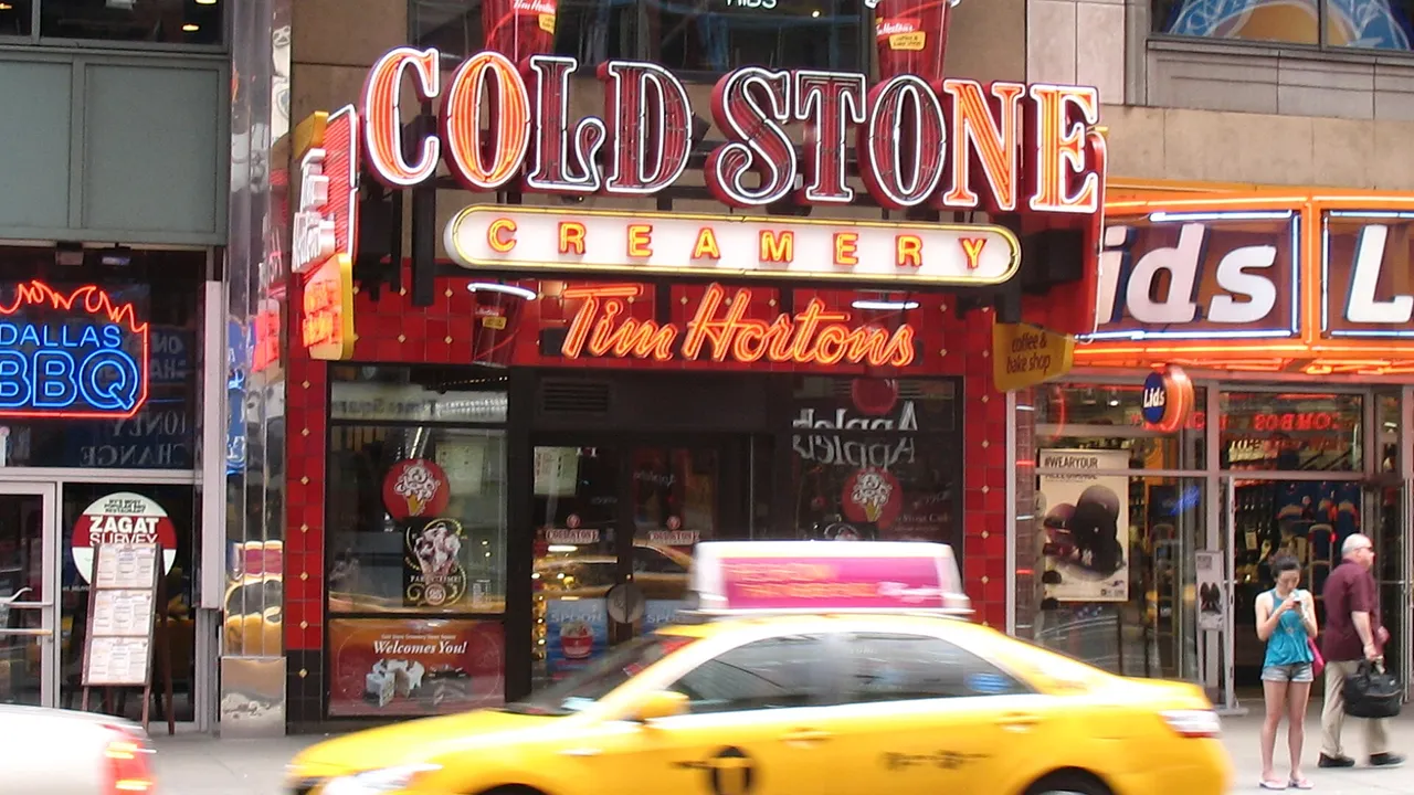 A Tim Hortons storefront with a neon sign on 42nd Street in New York City